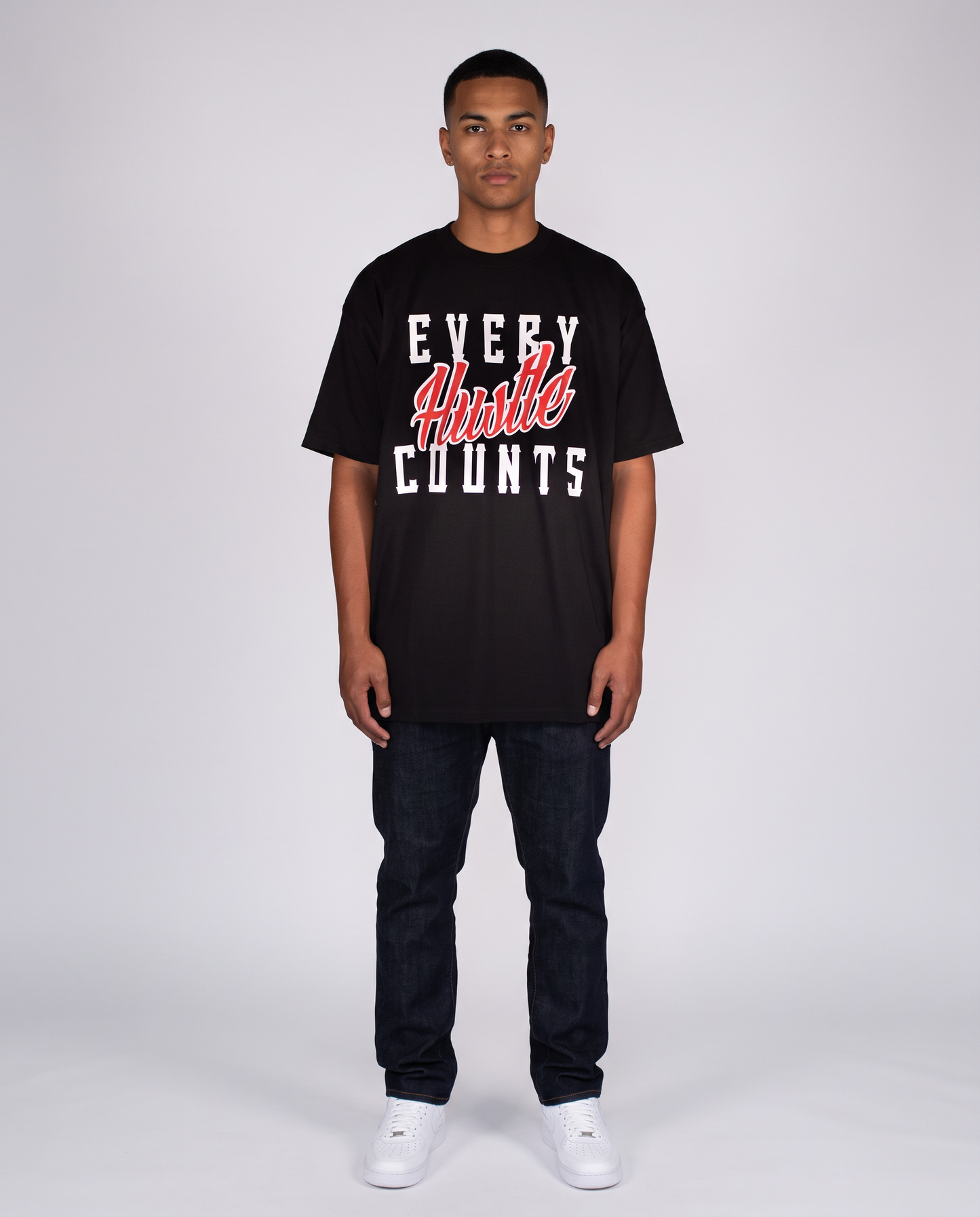 Model wearing the Every Hustle Counts Original EHC black t-shirt with jeans and white sneakers